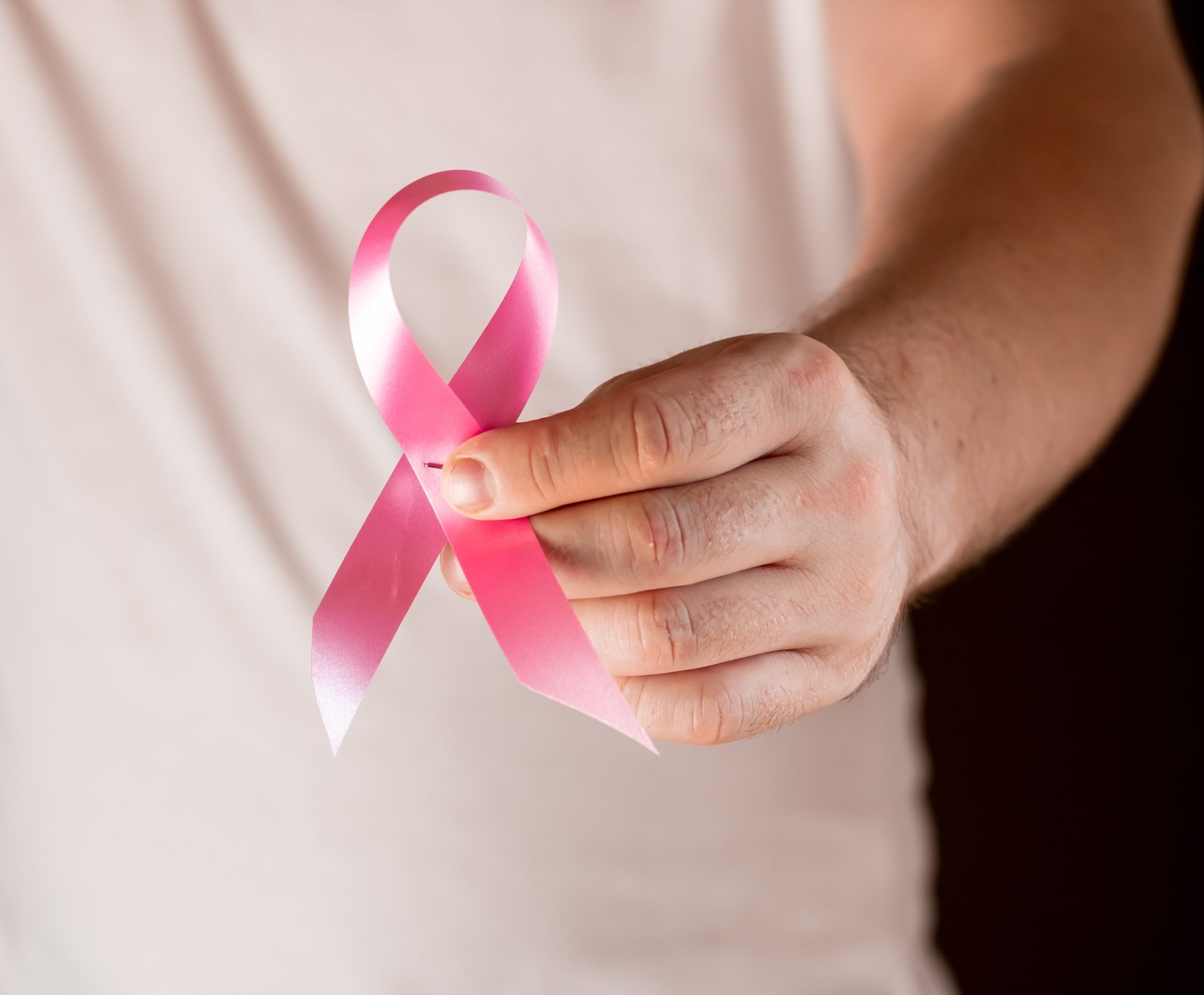 Closeup shot of a male holding the breast cancer symbol